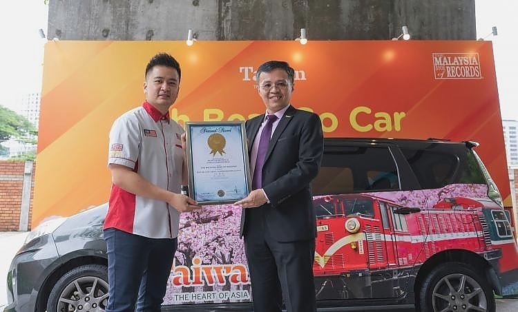 台湾观光局吉隆坡办事处主任周士弼（右）从马来西亚纪录大全私人有限公司市场及活动部副经理黄程运（左）手中接过《马来西亚纪录大全》颁发的“最多旅游品牌广告车”奖状